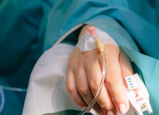 Kroplówki z glutationem: potencjalne skutki uboczne i bezpieczna częstotliwość wlewów Dłoń pacjenta z kroplówką dożylną i pulsoksymetrem