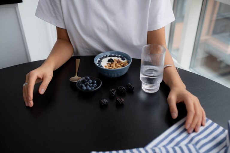 Granola z borówkami i jeżynami oraz szklanka wody na śniadanie